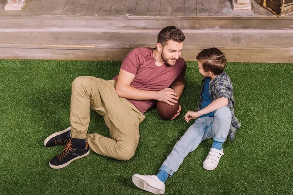 Padre con hijo acostado en la hierba - foto de stock