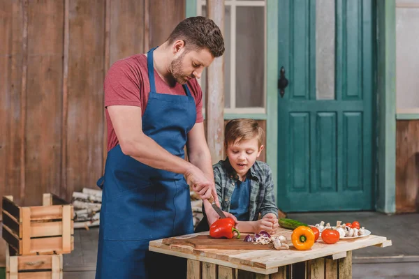 Padre e hijo cortando verduras - foto de stock