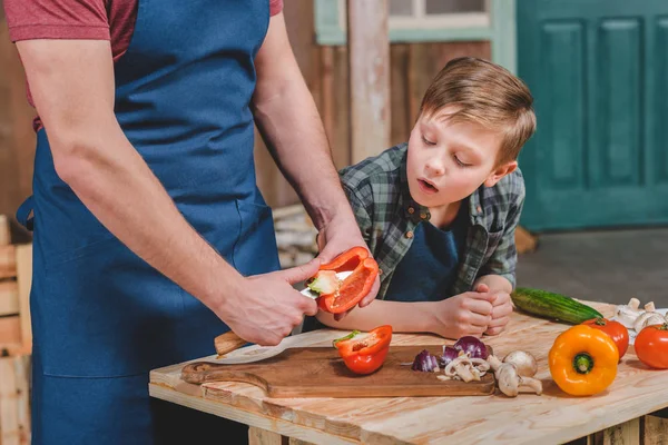 Pai e filho cortando legumes — Fotografia de Stock