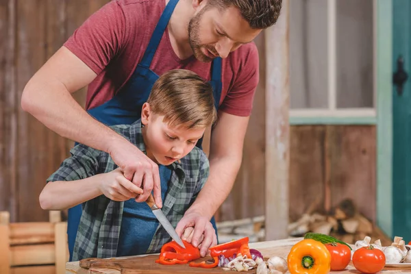 Padre e hijo cortando verduras - foto de stock