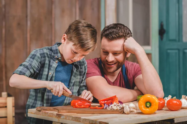 Pai e filho cortando legumes — Fotografia de Stock