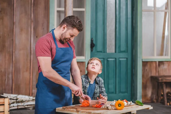 Pai e filho cortando legumes — Fotografia de Stock