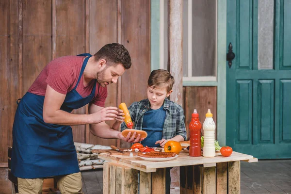 Padre e hijo cocinando hot dog - foto de stock