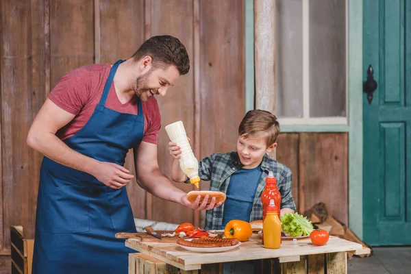 Father and son cooking hot dog — Stock Photo