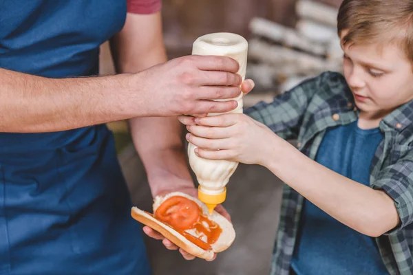 Padre e hijo cocinando hot dog - foto de stock