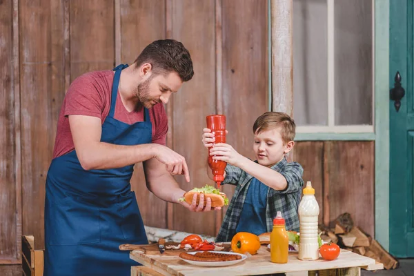 Padre e hijo cocinando hot dog - foto de stock