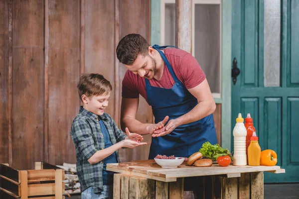 Father and son cooking burgers — Stock Photo