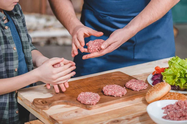 Padre e hijo cocinando hamburguesas - foto de stock