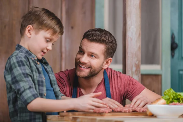 Father and son cooking burgers — Stock Photo