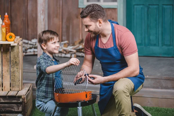 Padre e hijo preparando la parrilla - foto de stock