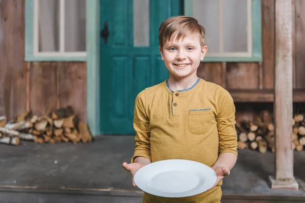 Niño sosteniendo plato vacío - foto de stock