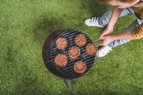 Boy cooking meat patties — Stock Photo