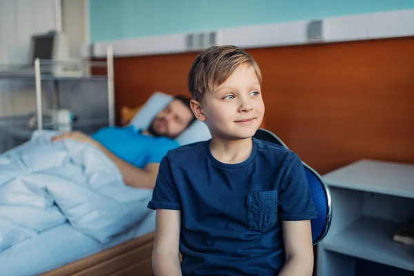 Filho sentado perto de pai doente na enfermaria — Fotografia de Stock