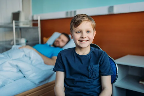 Sohn sitzt neben krankem Vater auf Station — Stockfoto