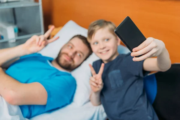 Padre e hijo tomando selfie en sala - foto de stock