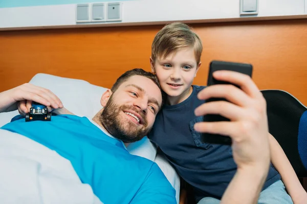 Padre e hijo tomando selfie en sala - foto de stock