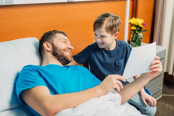 Son showing sick father drawings — Stock Photo