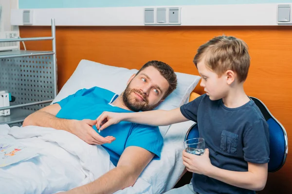 Son giving pills to sick father — Stock Photo