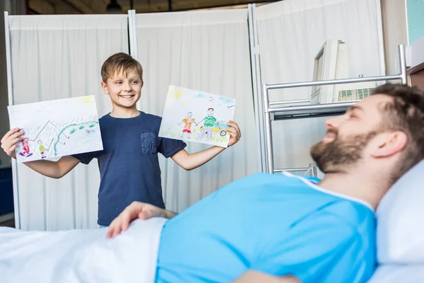 Сын показывает больного отца рисунки — стоковое фото