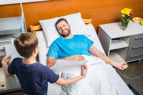 Son showing sick father drawings — Stock Photo