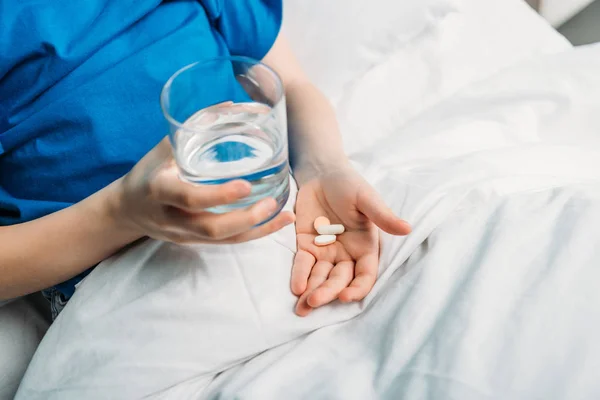 Niño con vaso de agua y medicinas - foto de stock