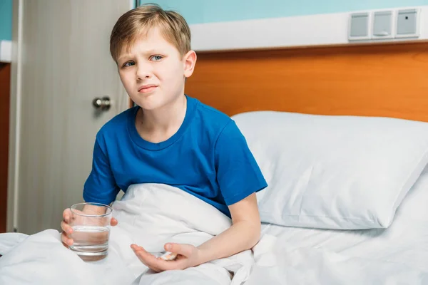 Junge mit Glas Wasser und Medikamenten — Stockfoto