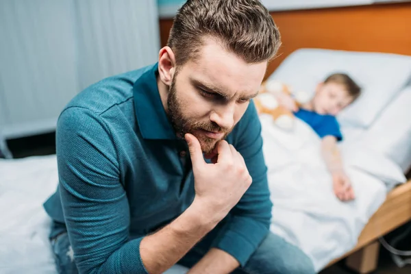 Padre cerca de hijo en cama de hospital - foto de stock