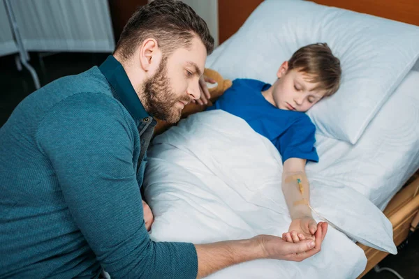 Padre cerca de hijo en cama de hospital - foto de stock