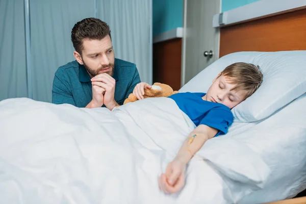 Padre cerca de hijo en cama de hospital - foto de stock