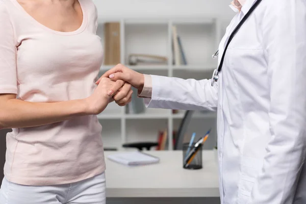 Doctor and patient holding hands — Stock Photo