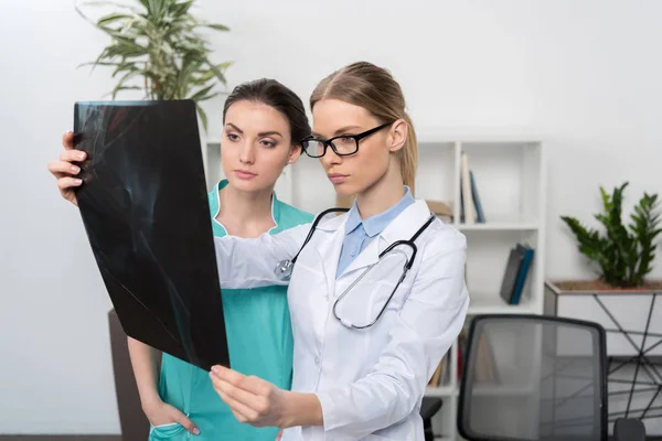 Médico y enfermera examinando rayos X - foto de stock