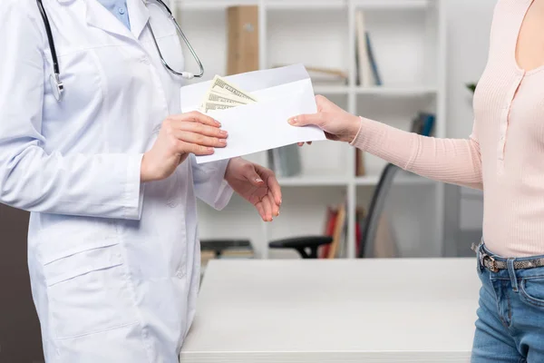 Patient giving money to doctor — Stock Photo