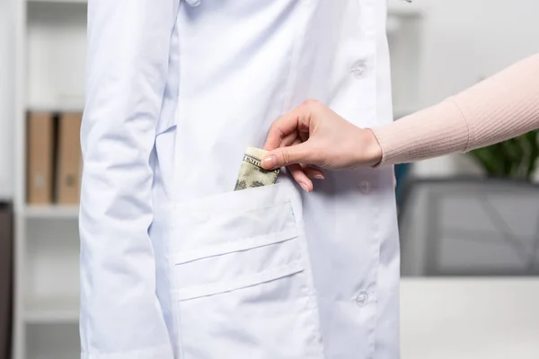 Patient mettre de l'argent dans la poche du médecin — Photo de stock