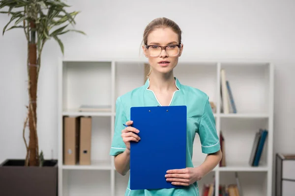 Doctor with clipboard looking at camera — Stock Photo