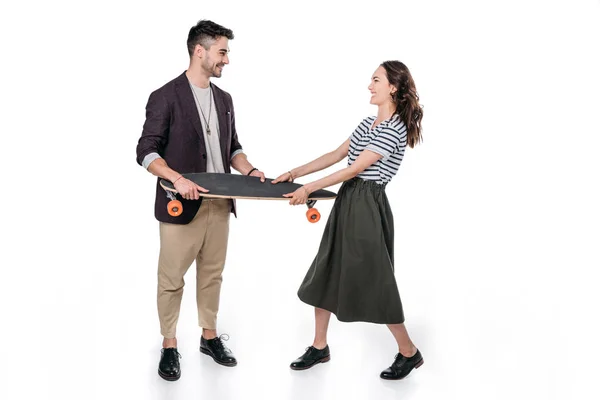 Smiling casual couple holding skateboard — Stock Photo