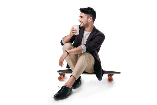 Homme boire une boisson tout en étant assis sur skateboard — Photo de stock