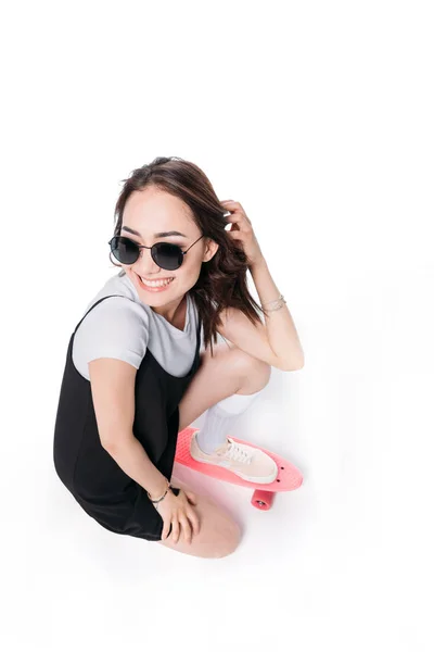 Smiling woman in sunglasses sitting on skateboard — Stock Photo