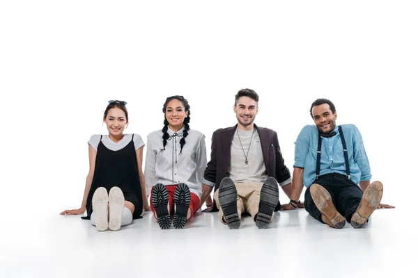 Sonrientes amigos multiétnicos sentados en el suelo - foto de stock