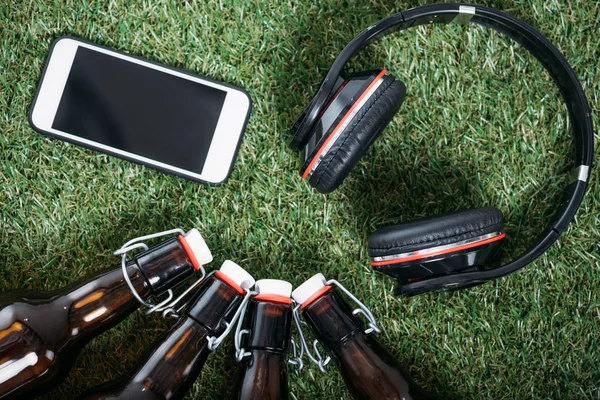 Garrafas de cerveja com smartphone e fones de ouvido — Fotografia de Stock