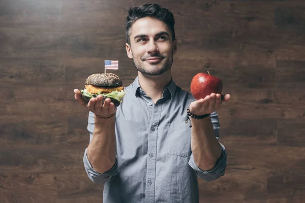 Человек с гамбургером и яблоком — стоковое фото