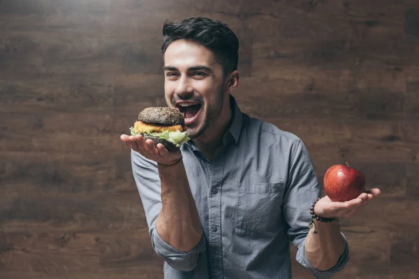 Hombre con hamburguesa y manzana - foto de stock