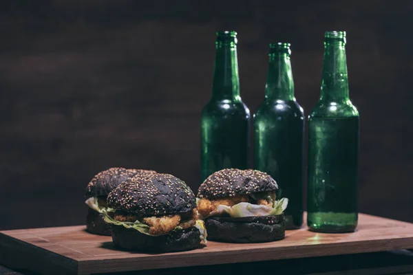 Tasty burgers and bottles on kitchen desk — Stock Photo