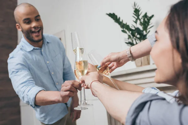 Amigos tintineo con copas de champán en casa - foto de stock