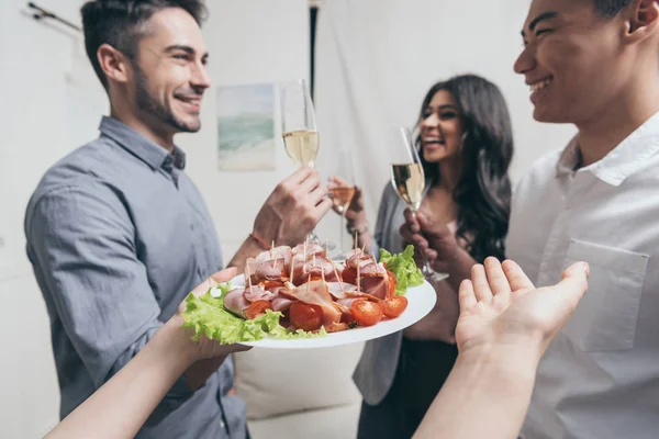 Mujer tratando a amigos con bocadillos en la fiesta - foto de stock