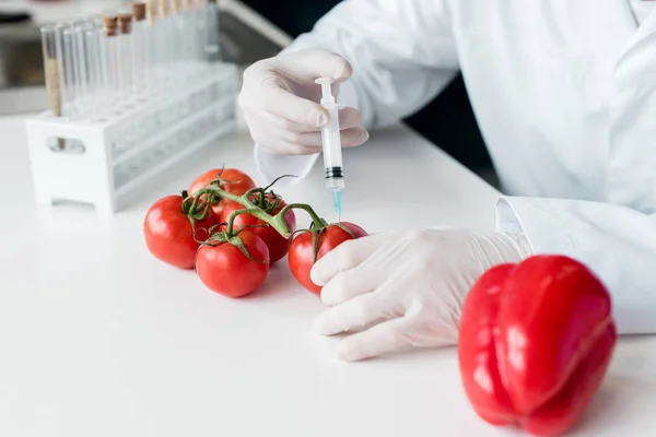 Científico con jeringa y tomates - foto de stock
