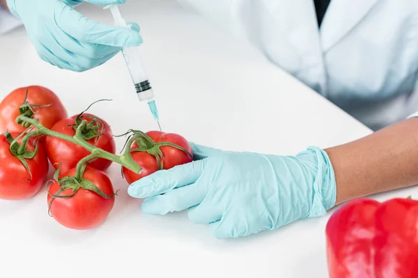 Scientist with syringe and tomatoes — Stock Photo