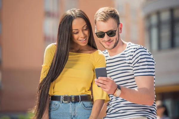 Coppia multietnica utilizzando smartphone — Foto stock