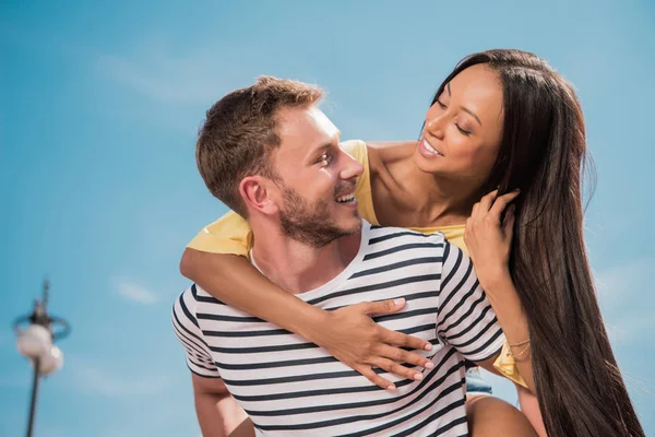 Multiethnic couple piggybacking in city — Stock Photo