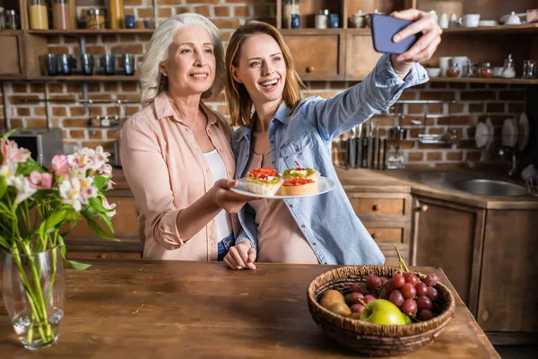 Mujeres tomando selfie en cocina - foto de stock