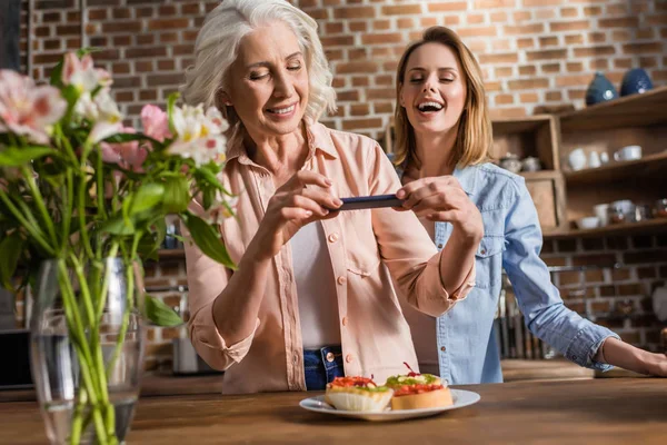 Mujeres fografiando comida en la cocina - foto de stock